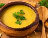 Vellutata di ceci cremosa in ciotola di legno, guarnita con prezzemolo fresco e accompagnata da crostini dorati.