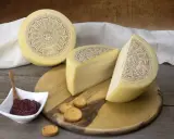Formaggio Pecorella, un pecorino in gravidanza, servito con marmellata e taralli su un tagliere di legno.