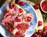 Bruschette con salame e varietà ciliegie giganti, guarnite con erbe aromatiche. Un connubio di sapori audace e invitante.