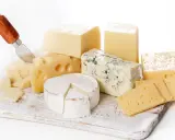 Varietà di formaggi senza lattosio: un pezzo di formaggio erborinato, un brie, formaggi a pasta dura e svizzero, pronti per essere gustati.