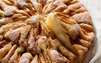 Una deliziosa torta di mele, cosparsa di zucchero a velo, con una fetta appena tolta che ne rivela la morbidezza.