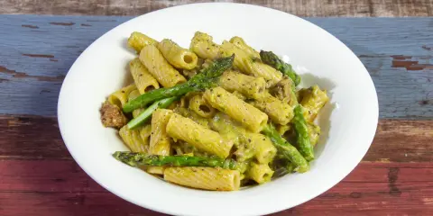 Piatto di pasta con asparagi e salsiccia, condita con una cremosa salsa verde.