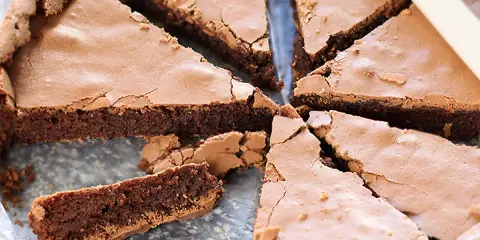 Una deliziosa torta tenerina al cioccolato, tagliata a fette triangolari, mostra la sua crosta croccante e il cuore morbido.