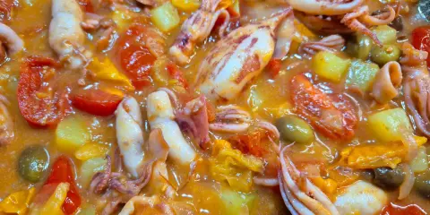 Totani in umido con pomodoro, patate e olive, un piatto saporito e colorato, pronto per essere gustato.