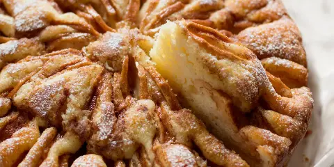 Una deliziosa torta di mele, cosparsa di zucchero a velo, con una fetta appena tolta che ne rivela la morbidezza.
