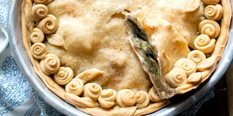 Torta salata con carciofi, decorata con rose di pasta frolla e foglie, pronta per essere gustata.