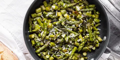 Asparagi in padella, saltati e cosparsi di parmigiano grattugiato, pronti per essere gustati.