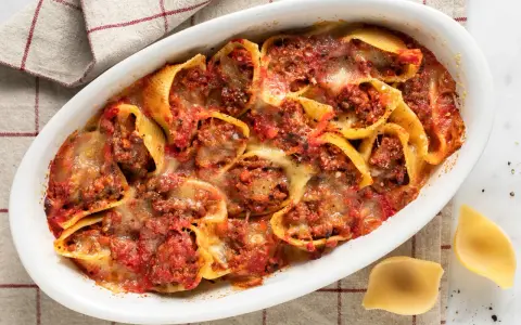 Conchiglioni ripieni al forno, un piatto invitante con pasta ripiena di carne, salsa di pomodoro e formaggio fuso, pronto per essere gustato.