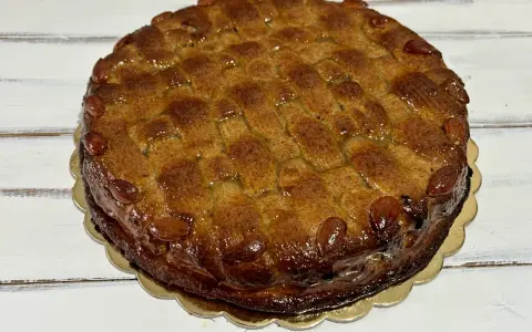 Deliziosa torta di mandorle siciliana, con una crosta dorata e mandorle intere che ne decorano il bordo.