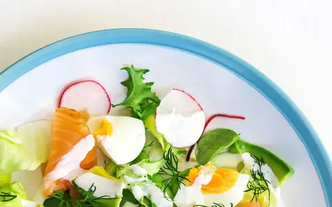 Insalata fresca con salmone, uova sode, avocado e ravanelli. Un piatto gustoso e leggero, ideale per chi cerca cibi senza carboidrati.
