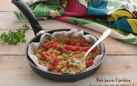 Alici gratinate in padella, un piatto semplice e gustoso con pomodorini e pangrattato, pronto per essere assaporato.