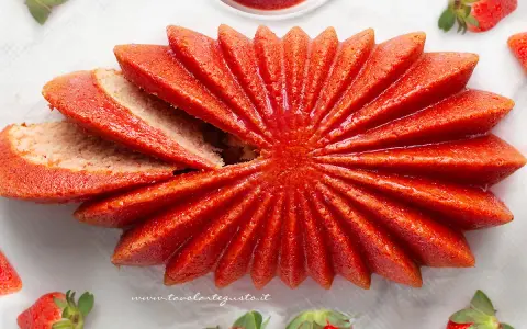Delizioso dolce a forma di fiore, con fette di torta alle fragole che si aprono come petali. Fresche fragole circondano questo dolce, invitando a gustare la sua dolcezza.