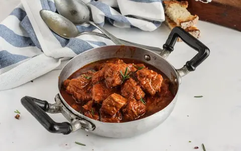 Un invitante spezzatino di vitello in umido, pronto per essere gustato. La ricetta perfetta per un pranzo domenicale.