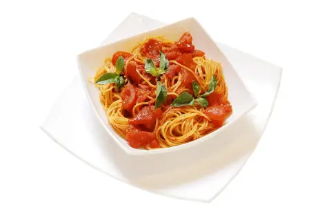 Un invitante piatto di spaghetti al pomodoro fresco, guarnito con foglie di basilico verde brillante.