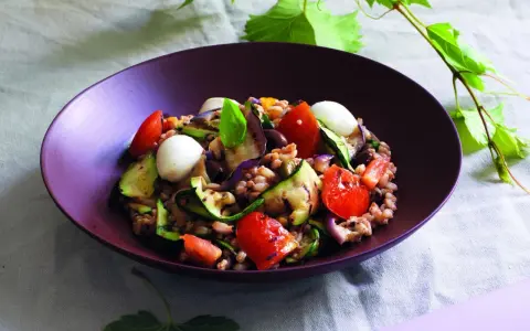 Insalata di farro estiva con verdure grigliate, pomodorini, mozzarelline e basilico, un piatto fresco e colorato.