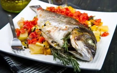 Orata intera cotta in friggitrice ad aria, servita con verdure miste e rosmarino.