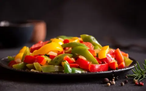 Peperoni colorati, cotti alla perfezione nella friggitrice ad aria, serviti su un piatto scuro. Un contorno sano e gustoso.