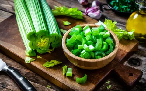 Sedano fresco, tagliato a pezzi in una ciotola, pronto per essere gustato. Verdure che non gonfiano la pancia, perfette per una dieta leggera e salutare.