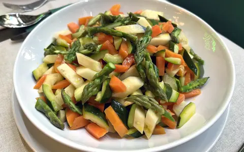 Un piatto invitante di verdure in padella: carote, zucchine e asparagi tagliati a pezzetti, cotti al punto giusto per un contorno sano e colorato.