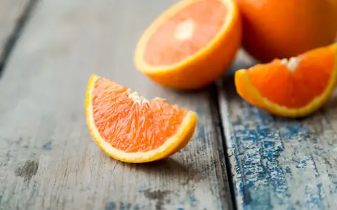 Arance fresche tagliate a spicchi su un tavolo di legno. Quante arance si possono mangiare al giorno? Dipende dal tuo fabbisogno di vitamina C.
