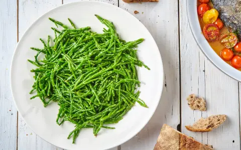 Piatto bianco colmo di asparagi di mare freschi e croccanti, pronti per essere gustati.
