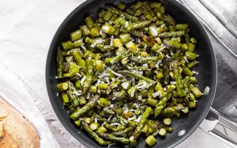 Asparagi in padella, saltati e cosparsi di parmigiano grattugiato, pronti per essere gustati.