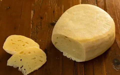 Formaggio di fossa, un sapore antico. Un pezzo di formaggio stagionato e due fette su un tavolo di legno rustico.