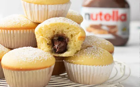 Muffin semplici con cuore morbido di Nutella, spolverati di zucchero a velo. Una ricetta golosa e facile da preparare.