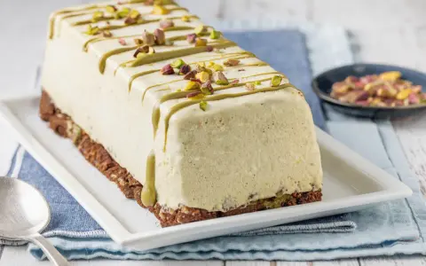 Semifreddo al pistacchio decorato con glassa verde e granella di pistacchi, su base croccante.