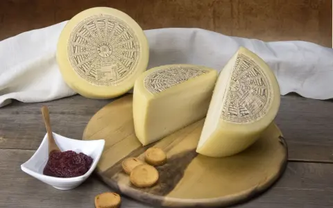 Formaggio Pecorella, un pecorino in gravidanza, servito con marmellata e taralli su un tagliere di legno.
