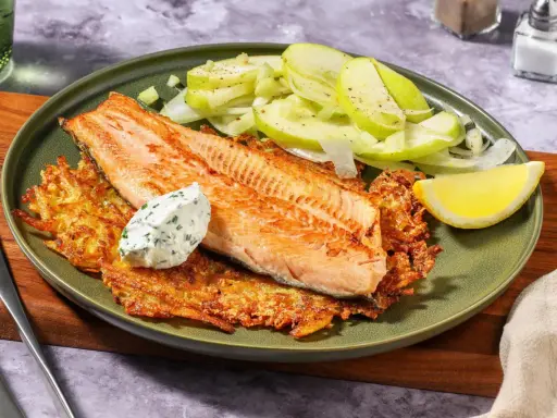 Filetto di salmone su croccanti rosti di patate, con insalata di mele e una quenelle di salsa alle erbe.