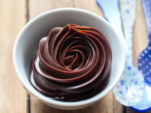 Una ciotola bianca piena di deliziosa crema al cioccolato, con un vortice perfetto.