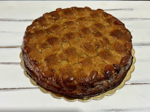 Deliziosa torta di mandorle siciliana, con una crosta dorata e mandorle intere che ne decorano il bordo.
