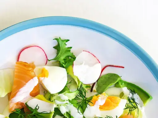 Insalata fresca con salmone, uova sode, avocado e ravanelli. Un piatto gustoso e leggero, ideale per chi cerca cibi senza carboidrati.