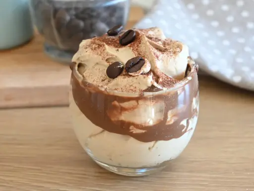 Deliziosa crema al caffè veloce in un bicchiere, guarnita con chicchi di caffè e cacao.