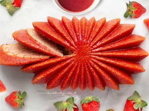 Delizioso dolce a forma di fiore, con fette di torta alle fragole che si aprono come petali. Fresche fragole circondano questo dolce, invitando a gustare la sua dolcezza.