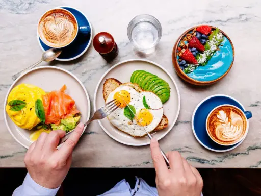 Colazione sana: uova, salmone, avocado, smoothie bowl e caffè. Ottimi esempi di colazione a basso indice glicemico per iniziare la giornata con energia.