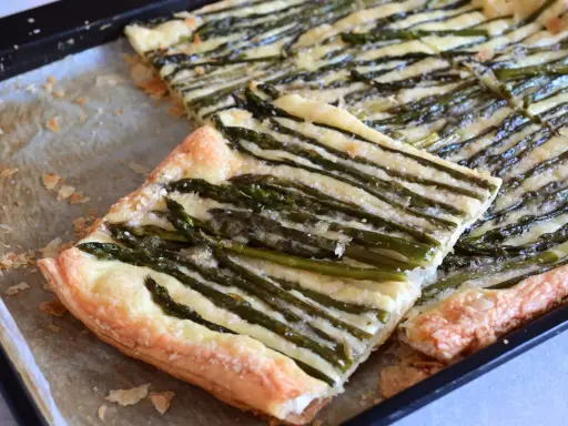 Deliziosa pasta sfoglia con asparagi e formaggio filante, appena sfornata su una teglia.