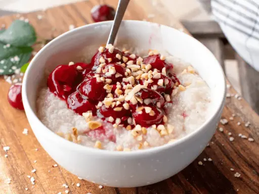 Una ciotola di porridge con ciliegie e nocciole tritate, una deliziosa colazione senza zuccheri.