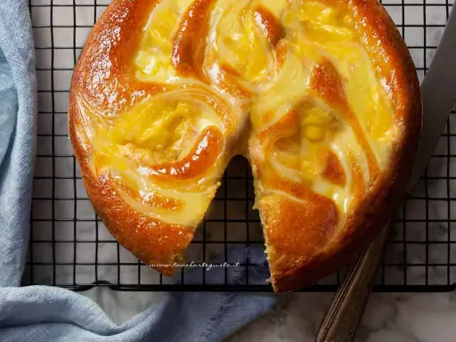 Torta soffice con un vortice di crema pasticcera dorata, appena sfornata e pronta per essere gustata.