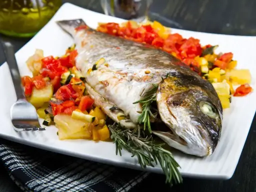 Orata intera cotta in friggitrice ad aria, servita con verdure miste e rosmarino.
