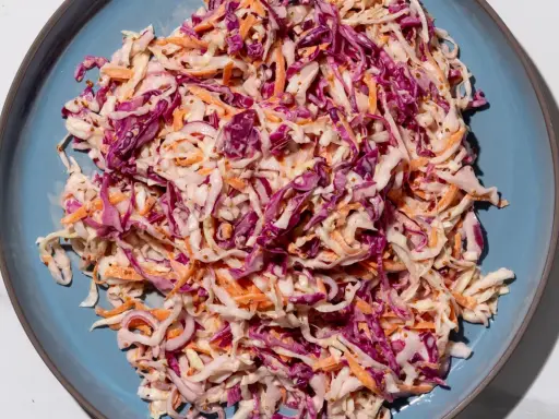 Insalata colorata con cavolo cappuccio rosso, carote e semi di senape, condita con una salsa cremosa.