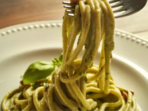 Trenette al pesto, un piatto invitante con pasta fresca avvolta in una salsa verde vibrante, guarnito con basilico.