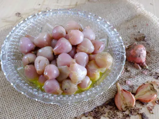 Lampascioni, bulbosi e saporiti, in una ciotola di vetro. Cosa sono? Delizie pugliesi sott'olio.
