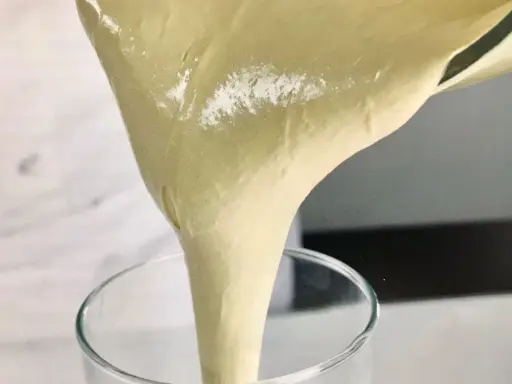 Versando una soffice pate a bombe in un bicchiere trasparente, pronta per una deliziosa preparazione.