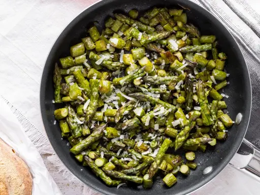 Asparagi in padella, saltati e cosparsi di parmigiano grattugiato, pronti per essere gustati.