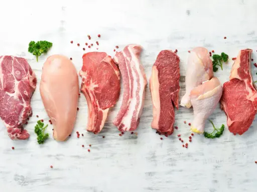 Varietà di carni: maiale, pollo e manzo. Carne bianca e rossa, con pepe rosa e prezzemolo.