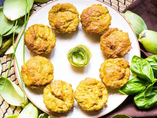 Muffin dorati, perfetti per una colazione proteica salata. Circondati da carciofi e basilico fresco, invitano a un pasto nutriente.