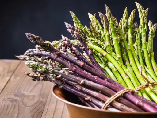 Mazzo di asparagi verdi e viola legati con spago, pronti per la cottura. Il tempo cottura asparagi varia a seconda della freschezza.