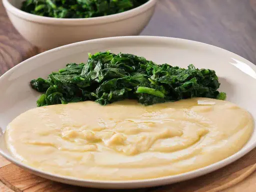 Piatto con purè di fave cremoso e spinaci saltati. Un contorno semplice e gustoso.